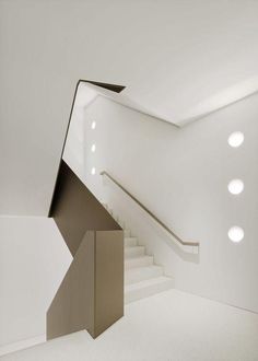 an empty white room with stairs and lights