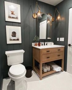 a white toilet sitting next to a sink in a bathroom under two pictures on the wall