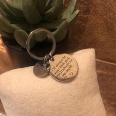 a keychain with a quote on it sitting next to a potted plant