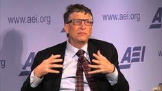 a man in a suit and tie sitting down talking to someone on the stage behind him