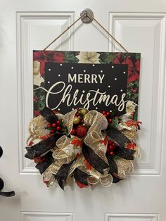 a christmas wreath hanging on the front door with merry christmas written in black and gold