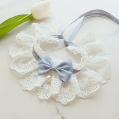 a close up of a necklace on a table with a flower and a ribbon around it