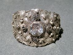 This fabulous 800 silver cuff is very Peruzzi in style with a faceted rock crystal center stone and ornate silver work. The piece is very detailed and is chockablock with roses, leave, scrolls, drops and etching. The center gemstone is 14mm in diameter and a multi faceted stone in perfect condition.  The stone is clear and colorless. The bracelet has a wonderful patina and feels great on your arm. It is not signed, so I don't know who created this masterpiece, but it is definitely in the Renaissance Revival style that is so prevalent in Fratelli Peruzzi's work. One of a kind piece for your collection. Width: 1.75" tapering to 5/8" at terminal. Inside measurement: 5 5/8" Gap: 1" Total: 6 5/8" Weight: 47 grams Hallmark: 800 Ships via USPS Priority Mail Thank you for shopping Teece Torre Vint Vintage Bracelet, Silver Work, Quartz Bracelet, Rock Crystal, Vintage Bracelets, Silver Cuff, Fashion Bracelets, Arm Band, Etching