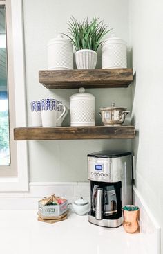 a coffee maker sitting on top of a counter next to two shelves filled with dishes