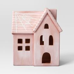 a pink ceramic house with a spider web on the roof