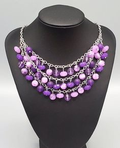 "Fairytale Timelessness": Varying in shape and opacity, a mismatched collection of light and dark purple crystal-like beads drip from the shimmery silver chains, creating an enchanted layered fringe below the collar. Features an adjustable clasp closure. Sold as one individual necklace. Includes one pair of matching earrings. Purple Beaded Chain Jewelry For Party, Purple Party Necklace With Chain Detail, Purple Party Jewelry With Adjustable Chain, Purple Chain Necklace For Party, Purple Dangling Beads Jewelry For Party, Purple Necklaces With Dangling Beads, Adjustable Purple Necklaces With Dangling Beads, Adjustable Purple Beaded Necklace With Dangling Beads, Adjustable Purple Necklace With Dangling Beads