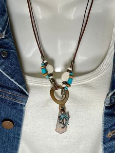 Detailed Picasso Jasper pendant hangs Lariat style with Turquoise, White and Turquoise Bone, Wood beads and a Mother of Pearl Loop to close. All on 2 leather cords, a 1mm dark brown and 2mm distressed brown. Picasso Jasper pendant is 1 1/2" long and 1/2" wide, around neck is 22" and total length of necklace is 24". A turquoise patina Octopus charm to the side that can be deleted of changed if you wish. To wear place open necklace around neck then put pendant thru the MOP ring. Adjust at will. No lead or nickel used. Please use the Last On, First Off approach. Stones discolor with lotions, perfumes, hairspray, sweat, chlorine, even some soaps, and will break if dropped. Bohemian Turquoise Necklace With Adjustable Cord, Bohemian Lariat Beaded Necklace With Adjustable Chain, Turquoise Lariat Necklace For Festivals, Bohemian Turquoise Lariat Necklace With Adjustable Chain, Adjustable Bohemian Lariat Necklace Nickel Free, Bohemian Brown Jewelry With Lobster Clasp, Bohemian Lariat Necklace With Lobster Clasp, Adjustable Lariat Necklace With Lobster Clasp, Bohemian Lariat Necklace With Adjustable Cord