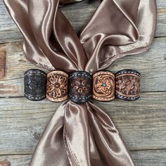 a brown scarf tied to a wooden table with two leather cuffs on top of it