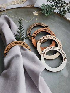 three wooden christmas ornaments sitting on top of a silver platter next to a white napkin