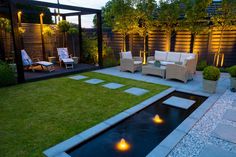 an outdoor living area is lit up at night with lights on the grass and lawn furniture