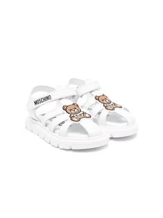 optical white/chamoisee/jet black calf leather caged design signature Teddy Bear motif logo print to the side branded footbed round toe front touch-strap fastening flat rubber sole White Sport Sandals With Buckle Closure And Round Toe, White Sport Sandals With Buckle Closure, Leather Sandals With Logo Strap, Leather Sandals With Logo Strap And Round Toe, White Closed Toe Sandals With Rubber Sole, White Leather Closed Toe Sport Sandals, White Leather Closed-toe Sport Sandals, White Closed-toe Leather Sport Sandals, White Sport Sandals With Branded Insole And Round Toe