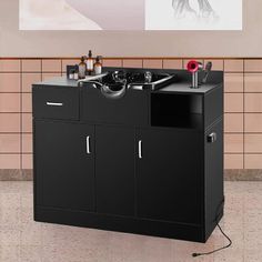 a black cabinet with two sinks and some bottles on the wall next to tiled walls