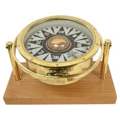 a gold and white compass on a wooden stand with two metal bars around the base