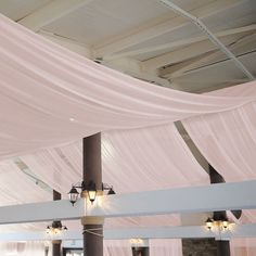 the ceiling is covered with pink draping and two lamps are on each side