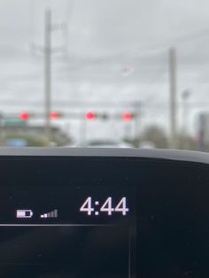 an electronic device with the time displayed on it's display in front of traffic lights