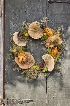 a wreath made out of leaves and flowers on a wooden door