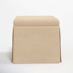 a beige ottoman sitting on top of a white floor