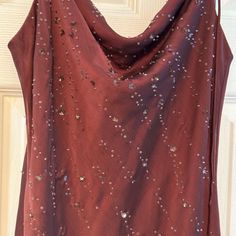 a red top with sequins on it hanging from a hanger in front of a door