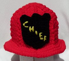 a crocheted red hat with black and yellow letters on the brimmed