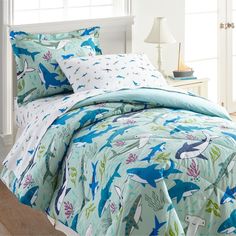 a bed covered in blue and green dinosaur comforters