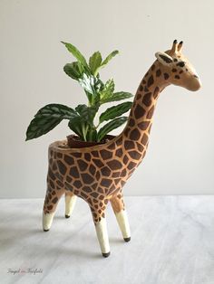 a giraffe planter with a potted plant in it