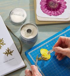 a person is painting flowers on a piece of paper