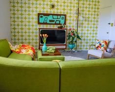 a living room with green couches and colorful wallpaper