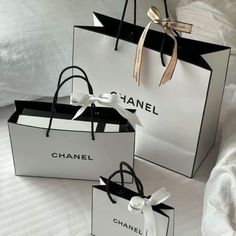 three black and white shopping bags with bows on the handles are sitting on a bed