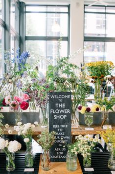 a flower shop with flowers in vases on the table and a sign that says welcome to the flower shop