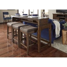 a living room filled with furniture and a wooden table surrounded by blue velvet couches