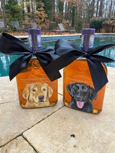 two bottles with dogs on them are sitting next to a swimming pool and one has a black bow