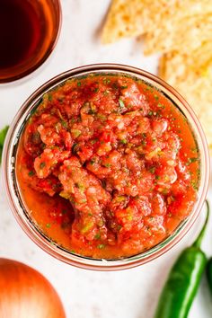 a glass bowl filled with salsa next to tortilla chips