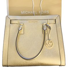 Michael Kors Large Dillion Satchel Crossbody Bag in Gold - The perfect gift comes with MK shopping bag and tags. No dust bag. Saffiano Leather Top Zip closure MK medallion hang charm on the front Gold tone hardware Michael Kors logo in front Flat bottom with protective feet Fully lined with matching MK Sateen Fabric Interior: 4 open pockets; 1 zippered pocket Approx Measurement: H 12” L 13” W 3.5” Dual handles drop 5.5" drop Adjustable/Removable shoulder crossbody strap 21"-25" drop Rectangular Saffiano Leather Bag With Gold-tone Logo Plaque, Classic Gold Satchel With Branded Hardware, Michael Kors Gold Travel Satchel, Michael Kors Gold Satchel For Travel, Modern Gold Satchel With Branded Hardware, Classic Gold Satchel For Shopping, Michael Kors Gold Rectangular Satchel, Luxury Michael Kors Bags In Saffiano Leather, Gold Michael Kors Rectangular Satchel