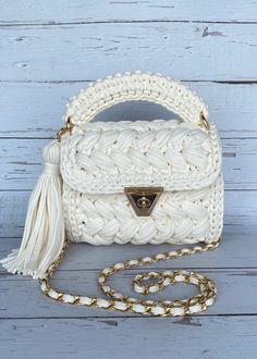 white crochet purse with tasselled handle and gold tone hardware on chain