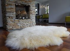 a large white sheepskin rug sitting on top of a hard wood floor next to a fire place