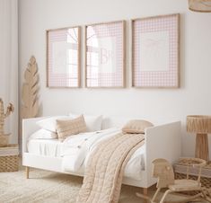 a white bedroom with pink and beige decor on the walls, two framed pictures above the bed