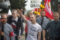 a group of people marching down the street with flags and signs on their backs,