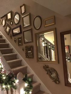 stairs decorated for christmas with garland and lights on the bannister railing, mirror frames and wreaths