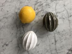 two lemons and an orange on a marble table with white swirls around them