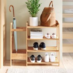 a wooden shelf with shoes and an umbrella next to a potted plant on top of it