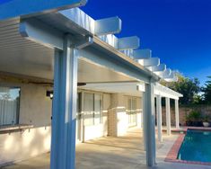 an outdoor patio with pool and pergolated roofing on the side of it