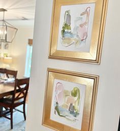 two paintings hanging on the wall above a dining room table