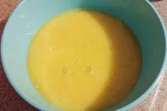 a blue bowl filled with yellow liquid on top of a table