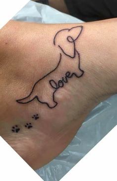 a small tattoo on the foot of a person with a dog's name and paw prints