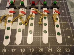 four snowmen made out of skis sitting on top of a table next to a ruler