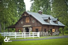 a barn with a white fence and trees in the background