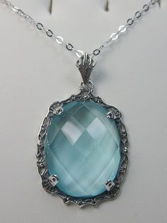 "Simulated Blue Aquamarine Necklace Bubble Design#P10 Custom Made Inspired by Victorian era designs, I now offer this lovely Antique reproduction in sterling silver. The flawless 22ct faceted simulated/Man-made blue Aquamarine is 24mm long (15/16th\") and 18mm in width (3/4th\"). The entire pendant is 1.5\" long and 7/8\" wide. The chain (if chosen) is between 16-18\" in length and is marked 925 as well. Notice the beautiful craftsmanship of the Victorian filigree setting. This pendant necklace Elegant Light Blue Round Pendant Necklace, Elegant Light Blue Necklaces For Gifts, Elegant Handmade Blue Necklaces, Vintage Blue Oval Pendant Necklace, Elegant Blue Filigree Necklace, Elegant Light Blue Oval Necklaces, Blue Aquamarine Pendant Necklace, Elegant Aquamarine Blue Jewelry, Elegant Blue Aquamarine Jewelry