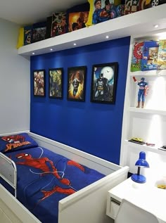 a bedroom with blue walls and pictures on the wall above the bed, along with white drawers