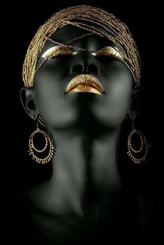 a woman's face with gold makeup and earrings on her head, in the dark