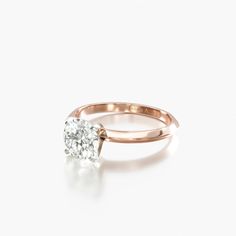 a rose gold engagement ring with a single diamond in the center, on a white background